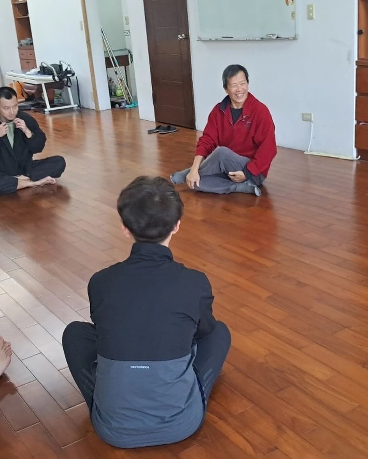 大家盤腿坐在木地板上圍成一圈分享，老師笑著
